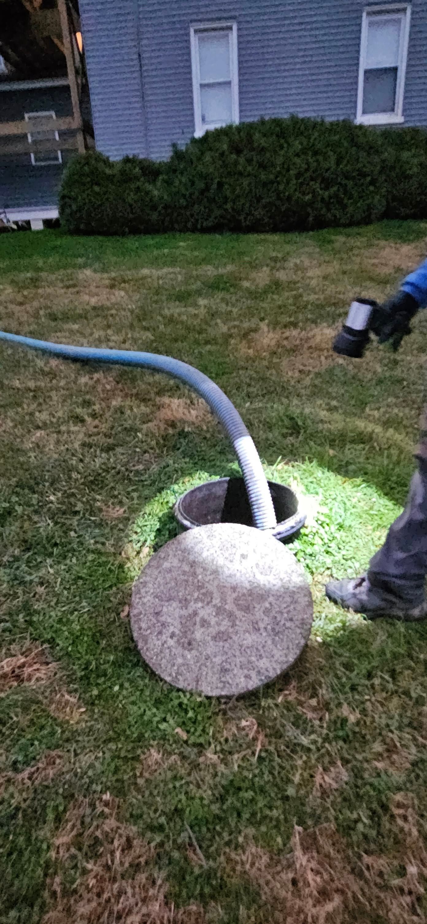 Person in neon suit inspecting pipes connected to green tanks in an outdoor setting. Person in neon suit inspecting pipes connected to green tanks in an outdoor setting.