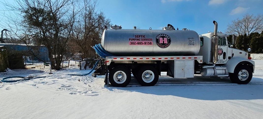 Person in blue suit and gloves with hose, pumping a septic tank in grass. Person in blue suit and gloves with hose, pumping a septic tank in grass.