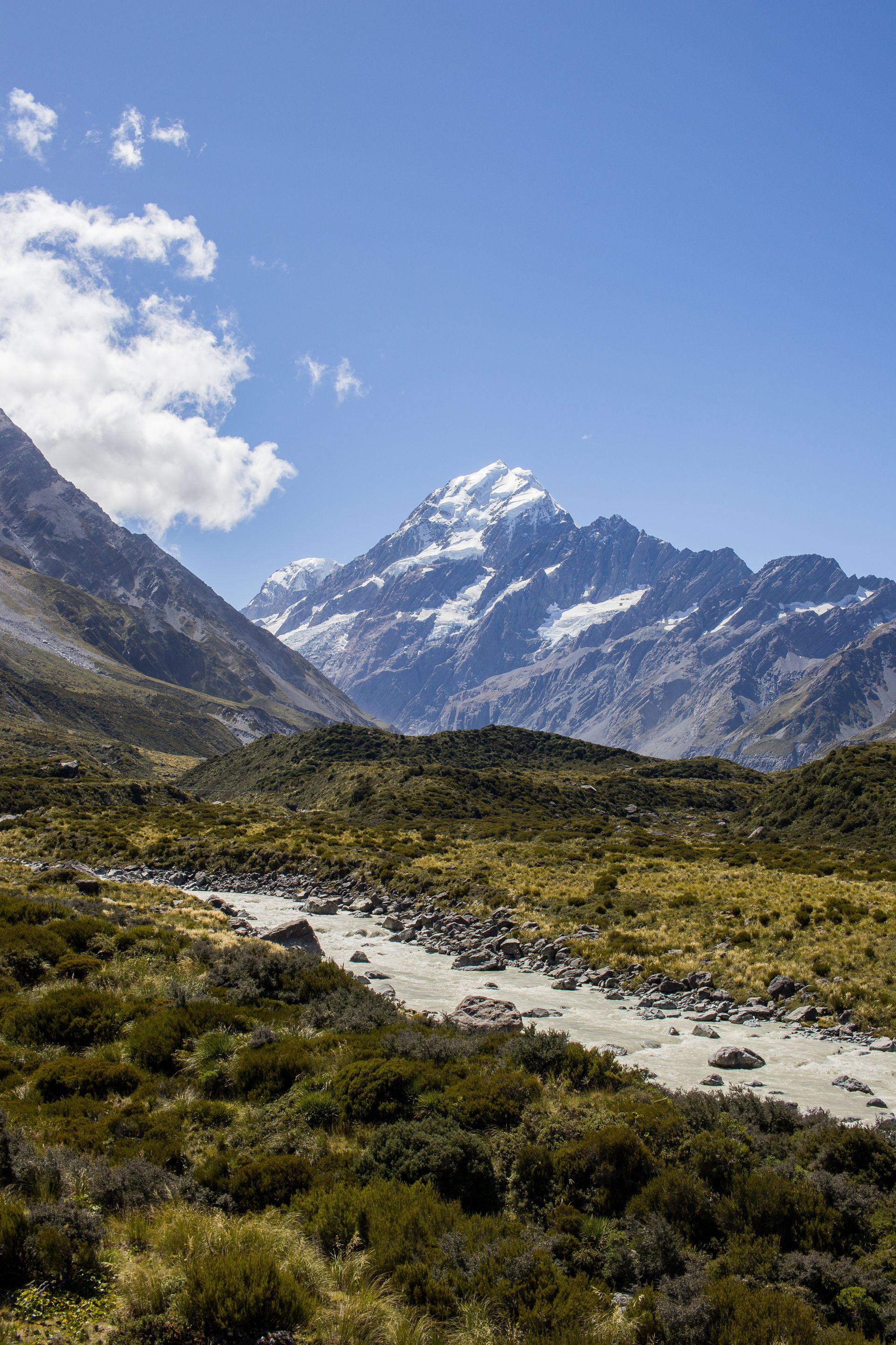 Een rivier die door een vallei bij Mt Cook in Nieuw-Zeeland stroomt met bergen op de achtergrond.