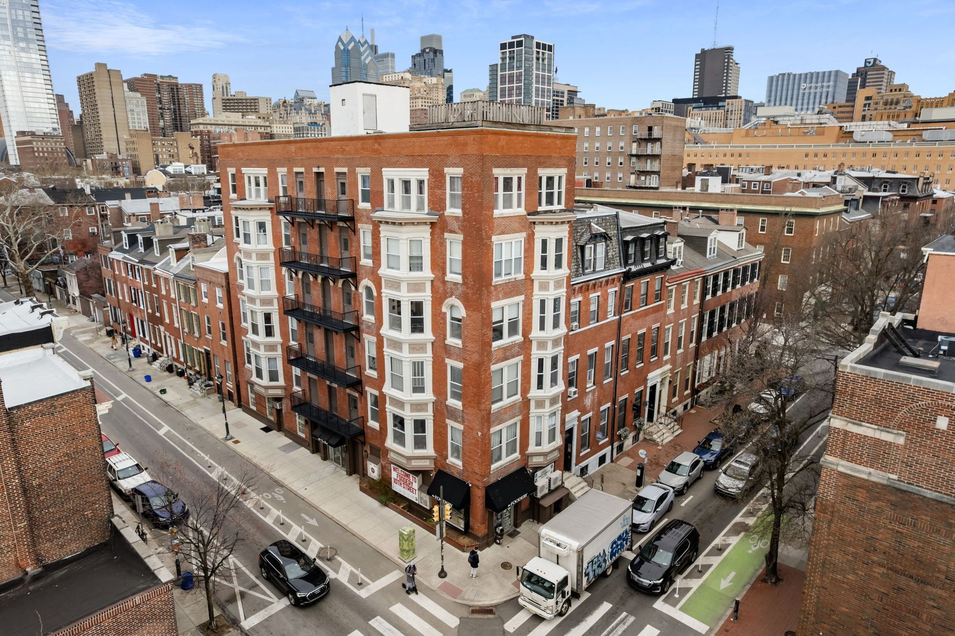 Two modern apartment buildings with angled roofs, balconies, and colorful facades against a blue sky.