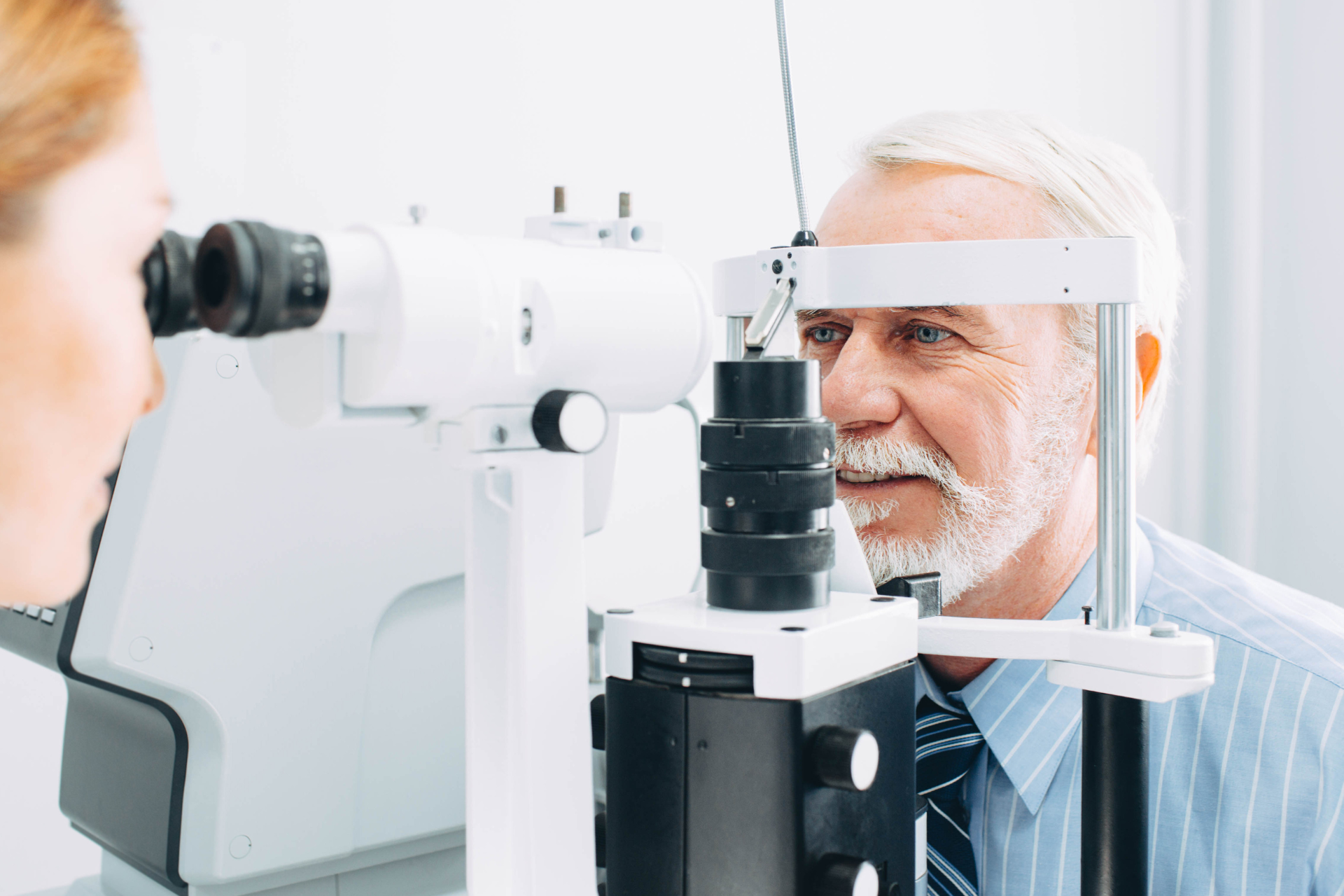 Patient undergoing an eye exam with an optometrist at a slit lamp microscope