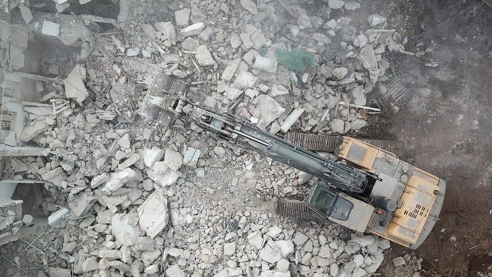 An aerial view of a bulldozer demolishing a building.