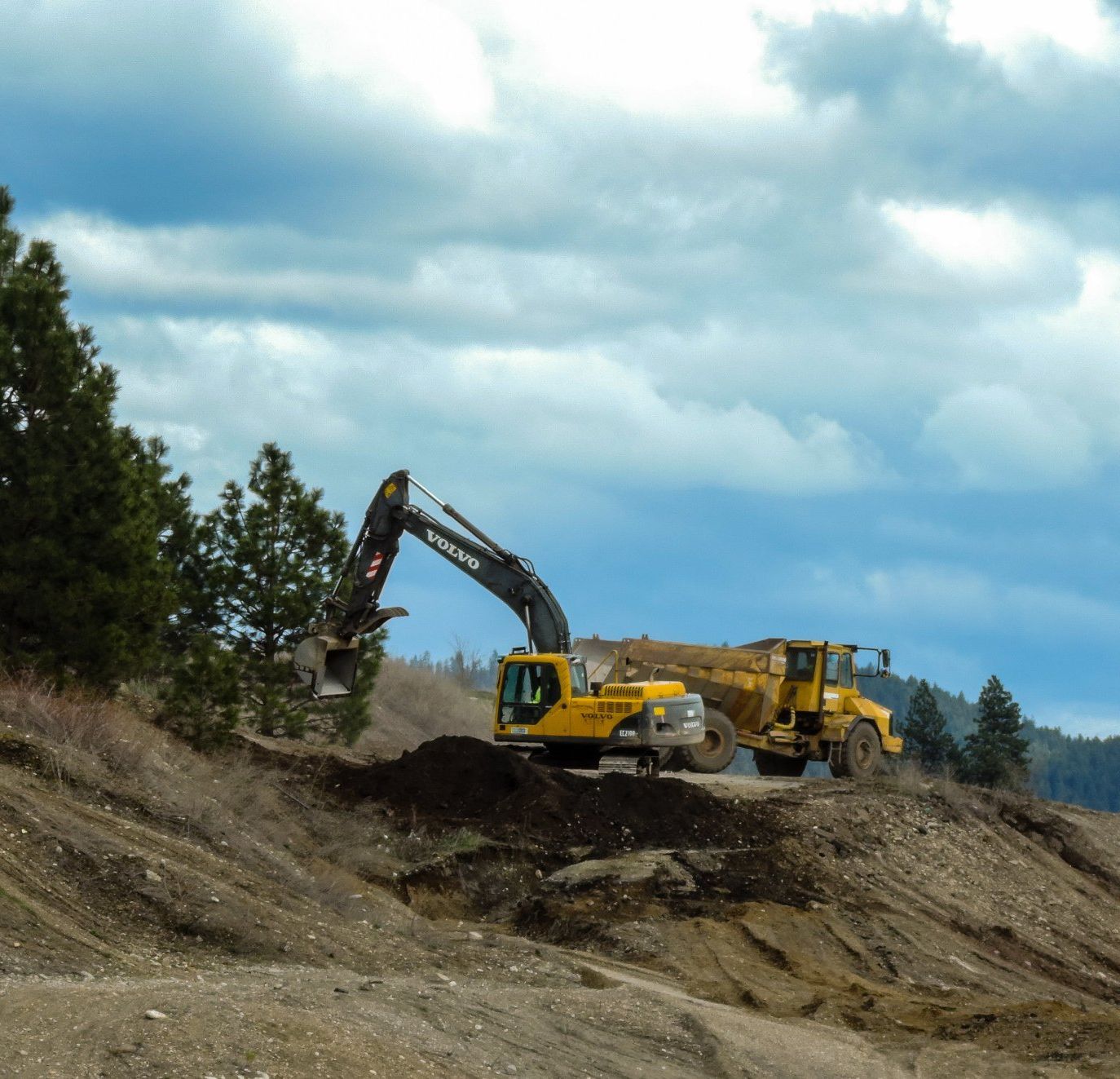 A volvo excavator is working on a dirt hill