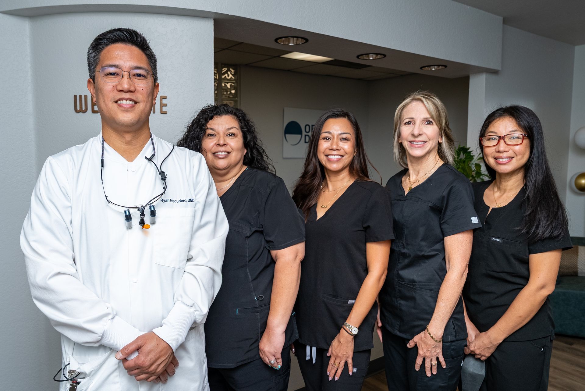 Five dental staff smiling at the camera in their office.