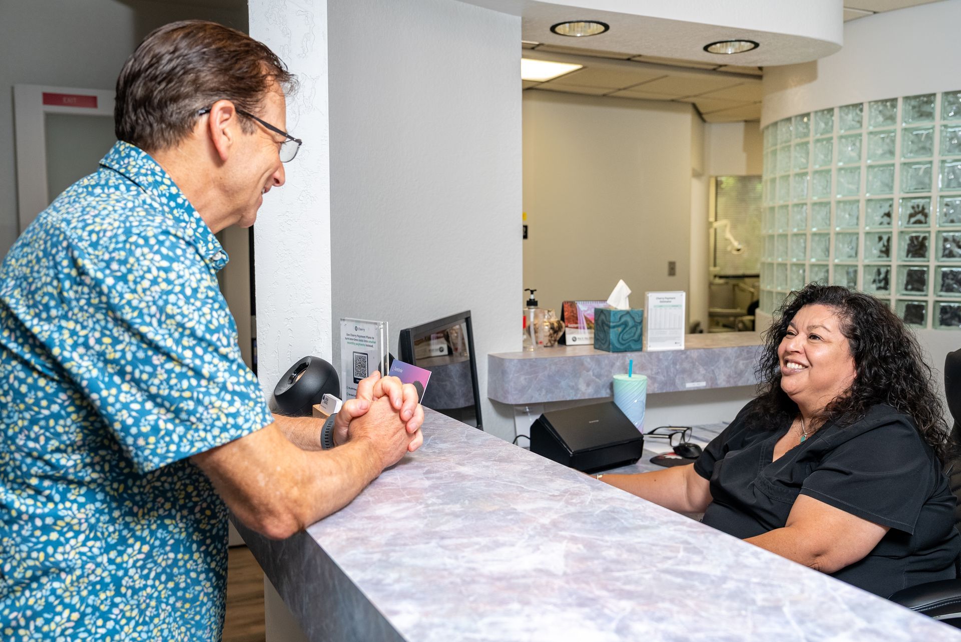 Man talking to receptionist at a desk in a medical office.