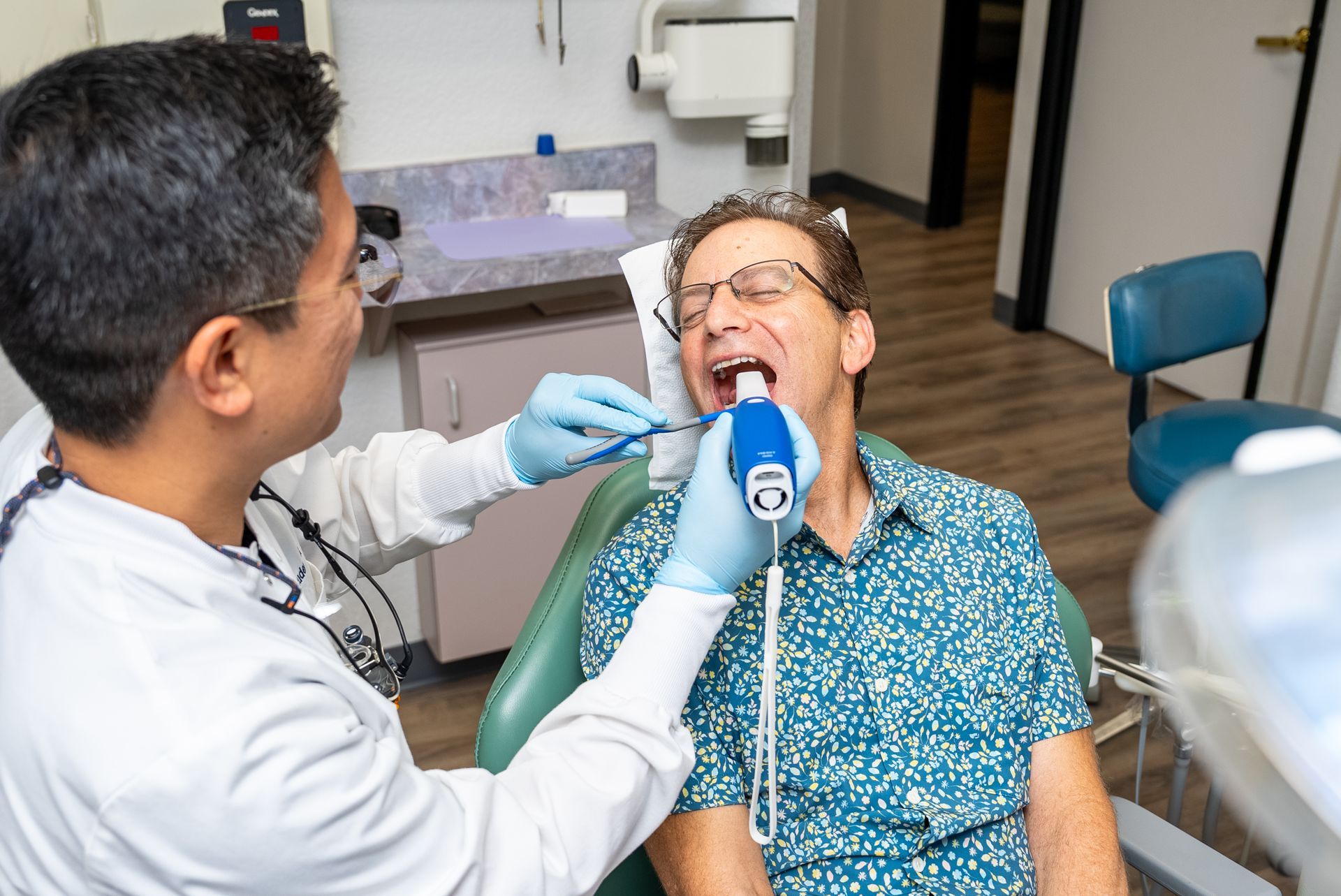 Dentist examining patient's mouth with tool in dental office.