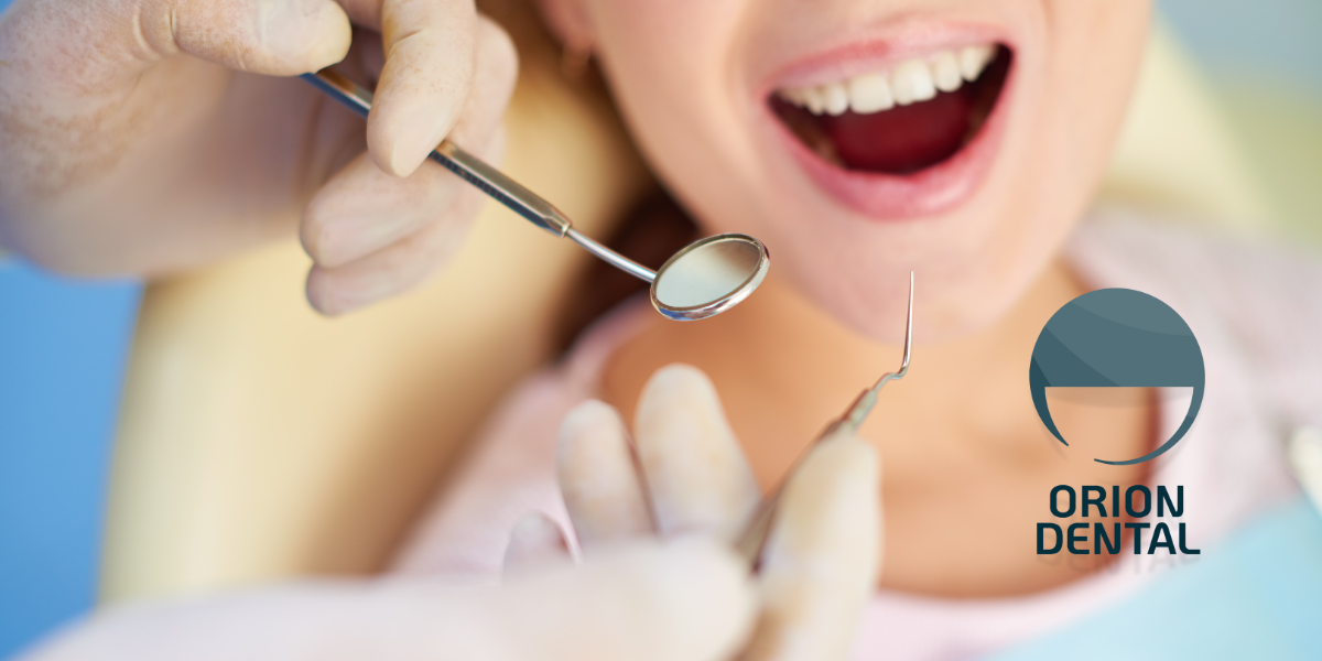 Dentist examining a patient's open mouth with dental tools.