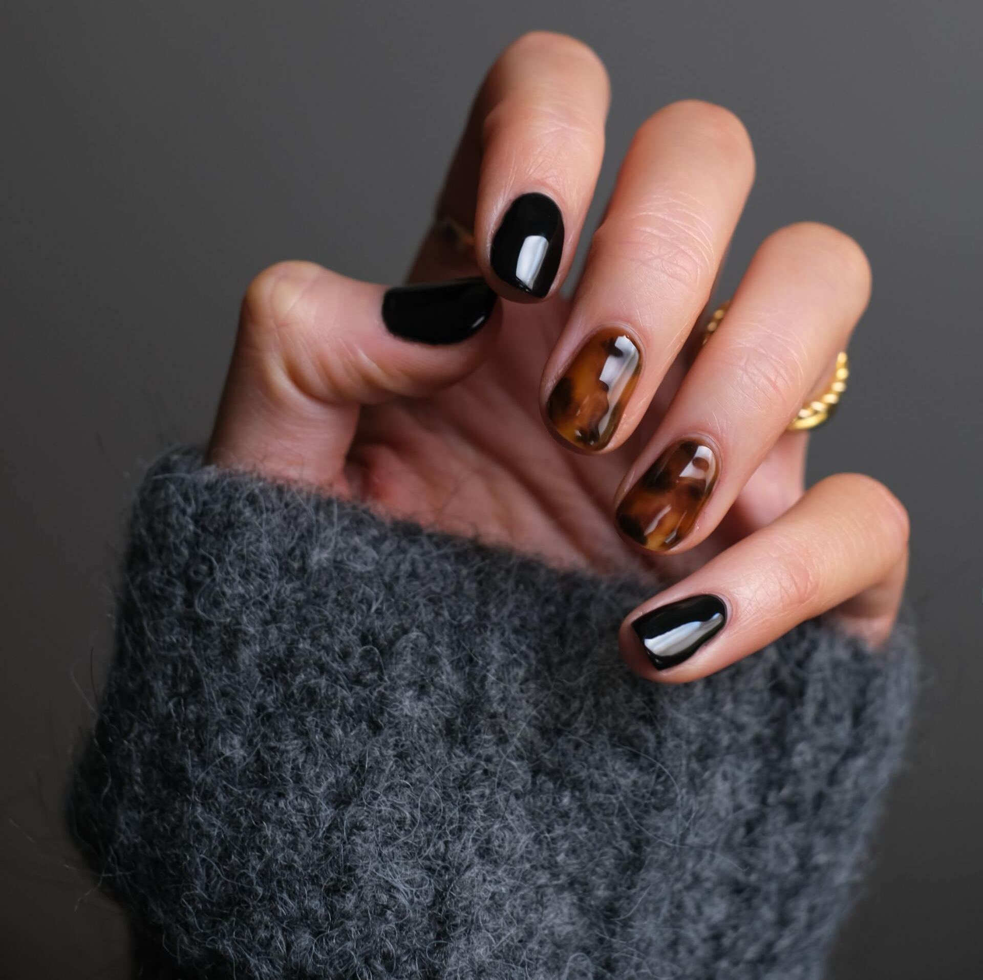 A close up of a woman 's hand with black and brown nails