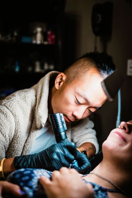 Asian man, Black gloves, focus on the process. tattoo artist, gay tattoo artist, fineline tattoo artist, tattoo,