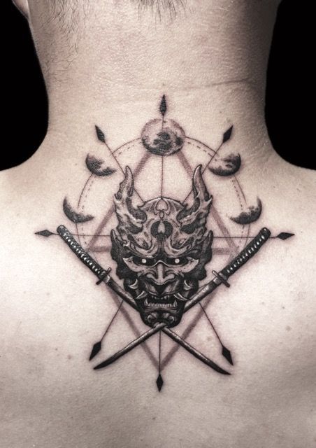 Tattoo of a horned demon mask with crossed swords and moon phases on the back of a neck.