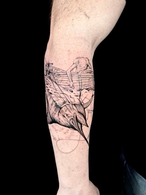 Tattoo on forearm: a stylized marlin fish leaping from water, with a small human figure on a boat deck.
