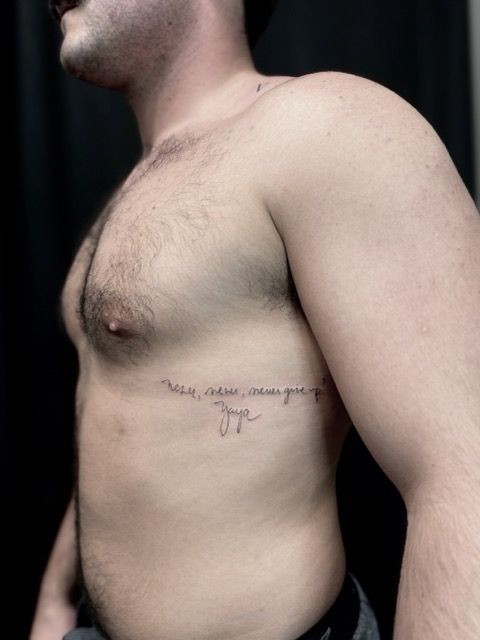 Man with a torso tattoo, side view. Tattoo is a script that reads 
