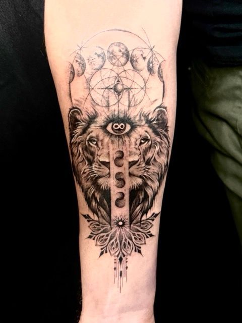 Lion tattoo with an eye, moon phases, geometric designs, and floral elements.