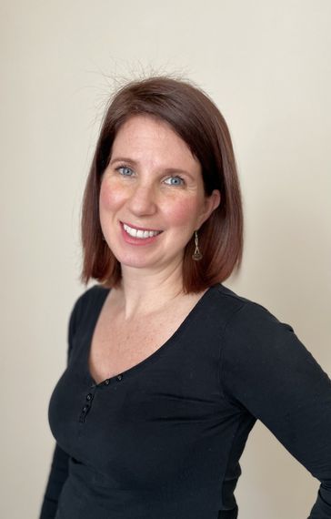 A woman in a black shirt is smiling for the camera.