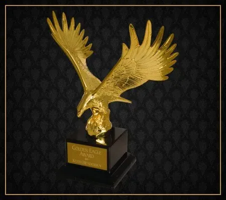 A gold eagle statue with a black background