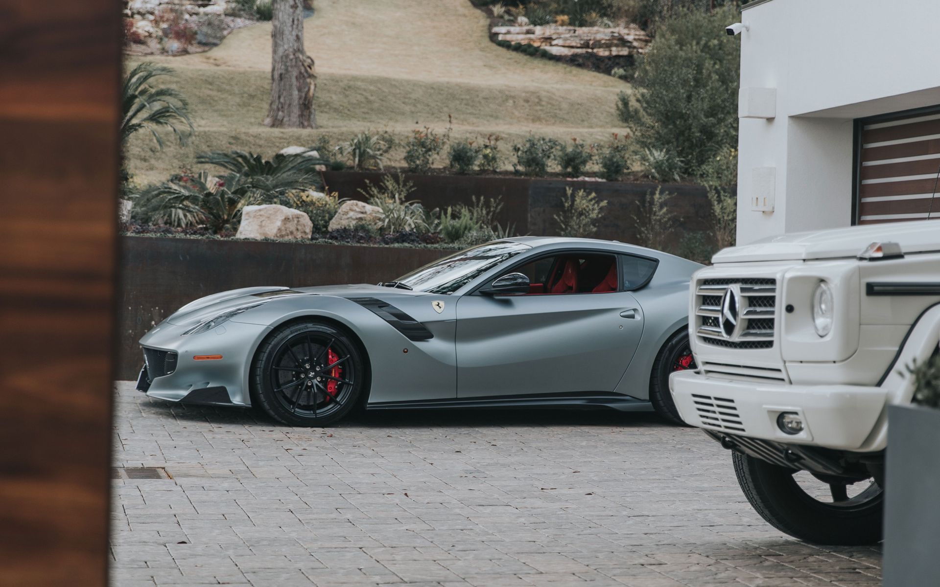 A ferrari f12 tdf is parked in a driveway next to a mercedes benz g63.