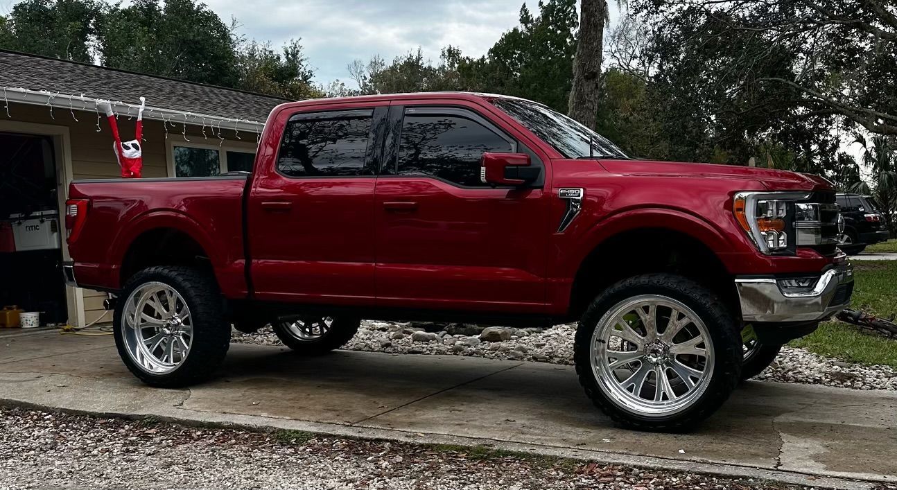 A red pickup truck is parked in a driveway in front of a house.