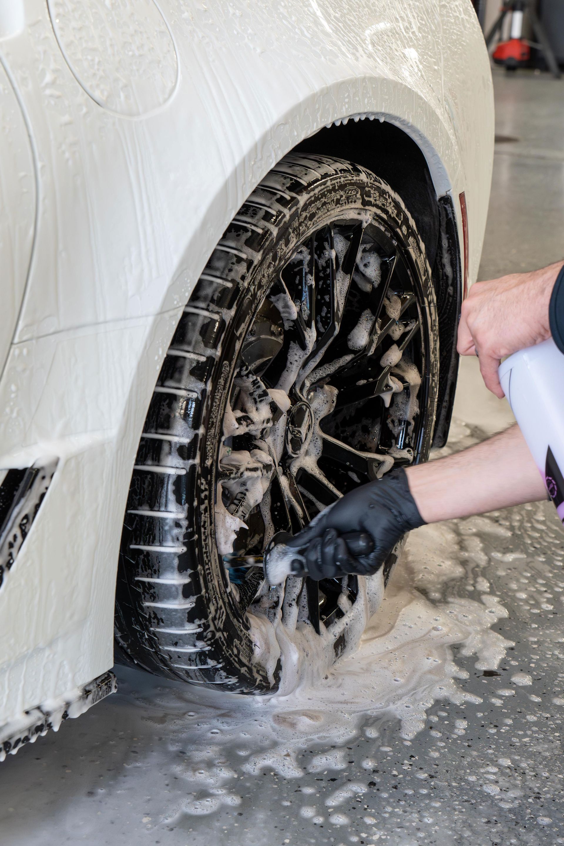 A person is washing a car wheel with a brush.
