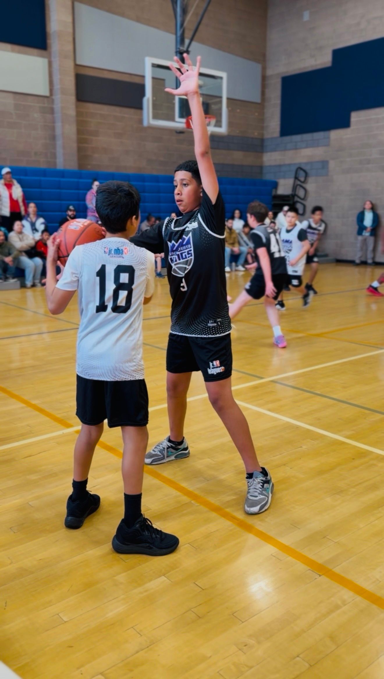 Two basketball players contest a shot under the hoop in a gym during a game
