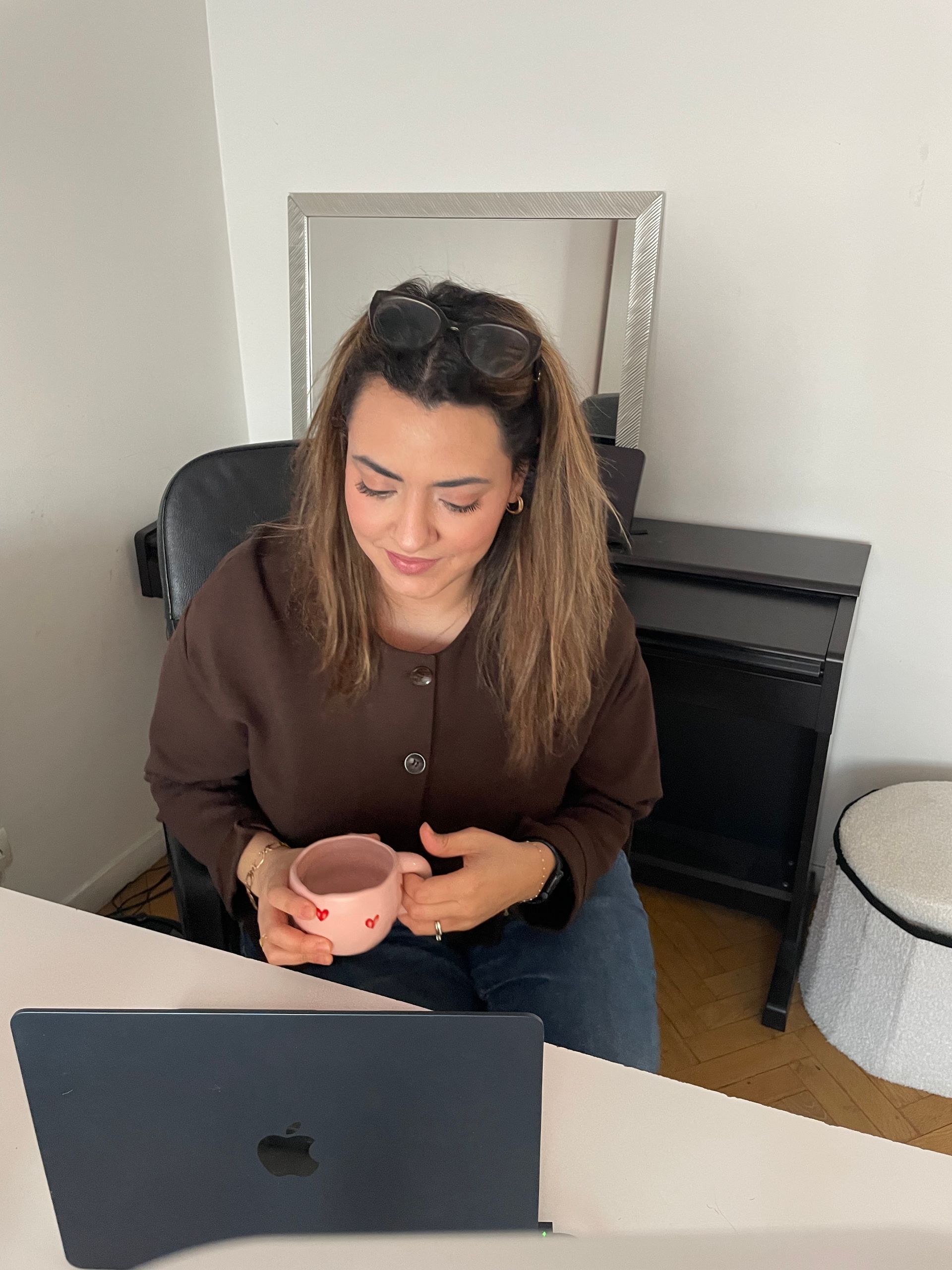 Une personne en chemise rayée regarde un mur recouvert de papiers, de croquis et de schémas.