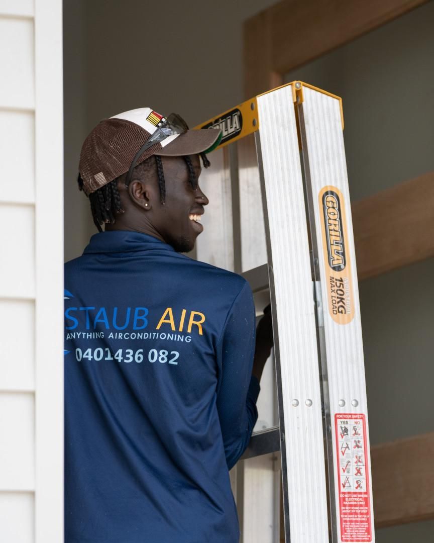 A Man Wearing a Staub Air Shirt Is Standing on A Ladder — Staub Air in Garbutt, QLD
