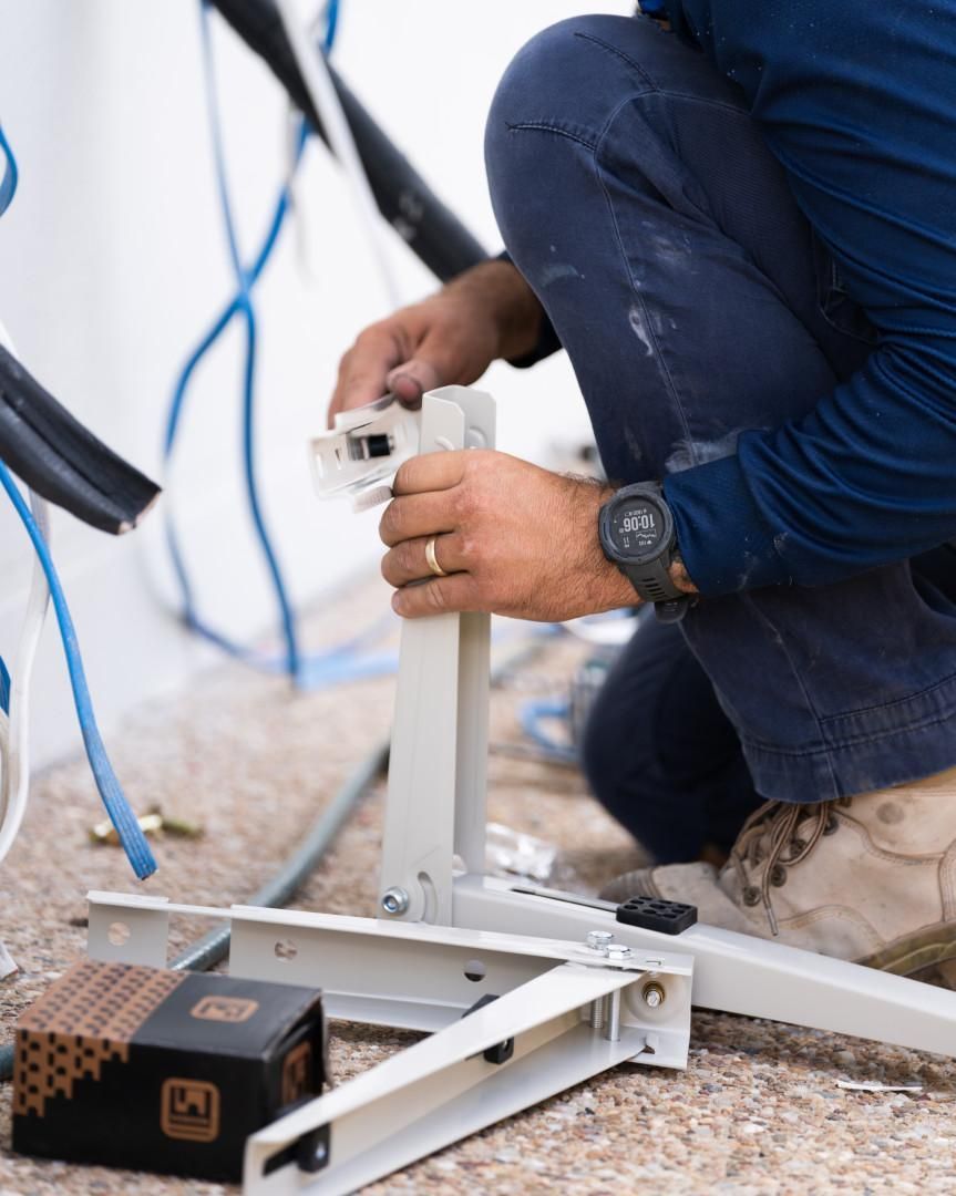 A Man Wearing a Watch Is Kneeling Down and Working on A Piece of Equipment — Staub Air in Garbutt, QLD