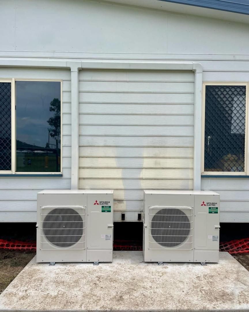 Two Air Conditioners Are Sitting in Front of A White House — Staub Air in Garbutt, QLD