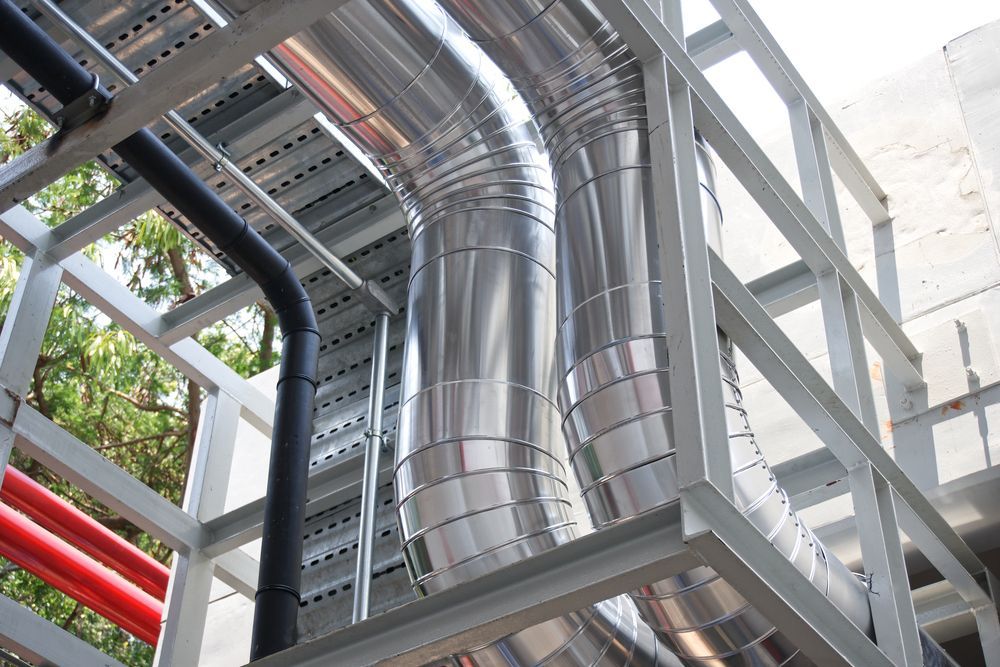 A Man Is Working on An Air Conditioner with A Staub Shirt On — Staub Air in Garbutt, QLD