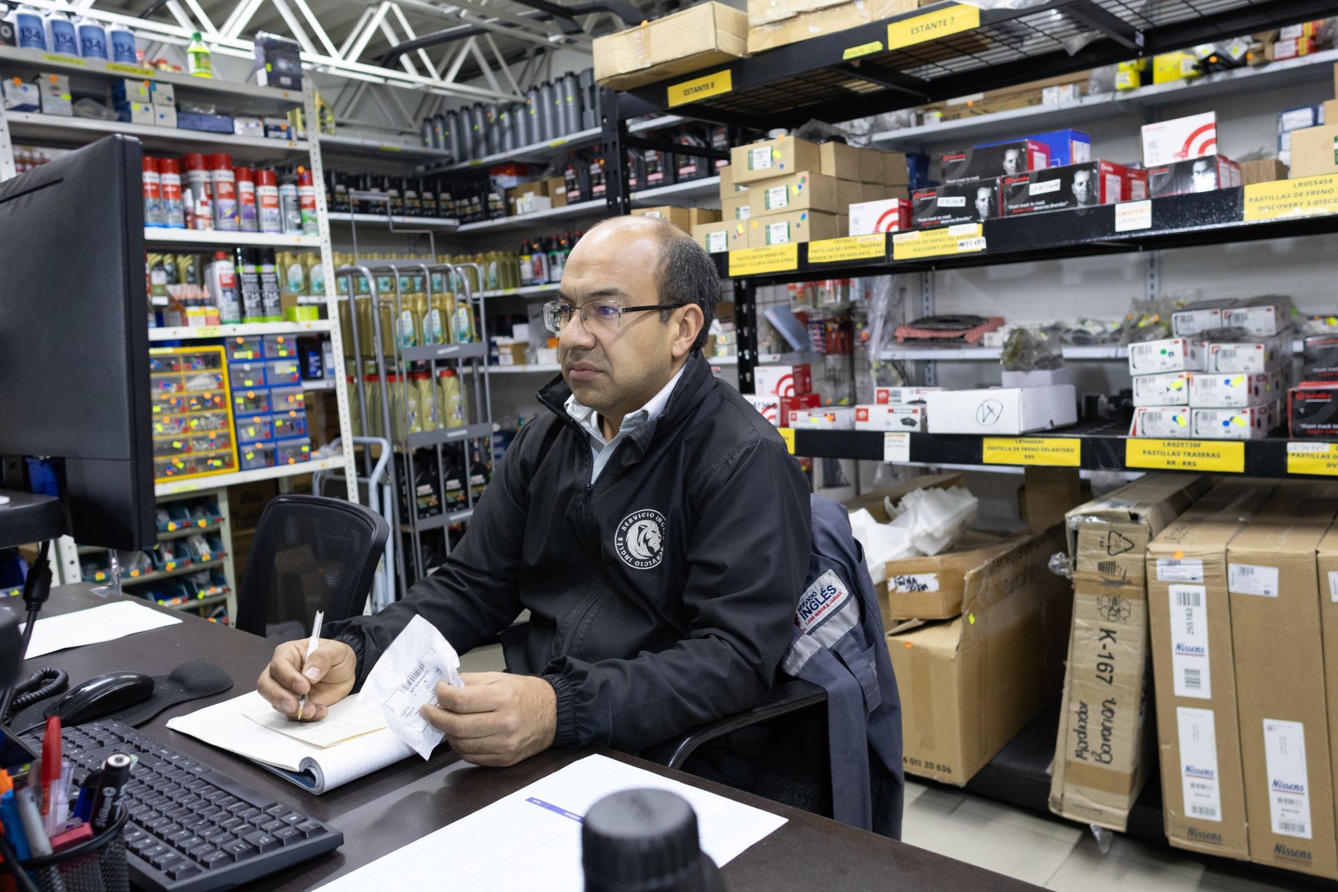 Un hombre está sentado en un escritorio frente a una computadora en una tienda.