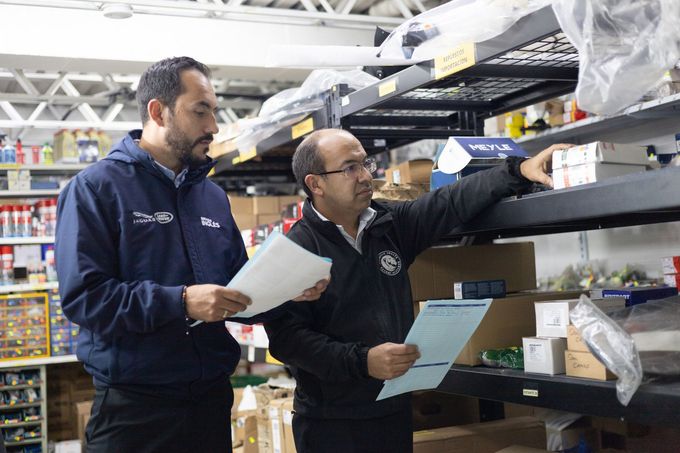 Dos hombres miran un trozo de papel en un almacén.