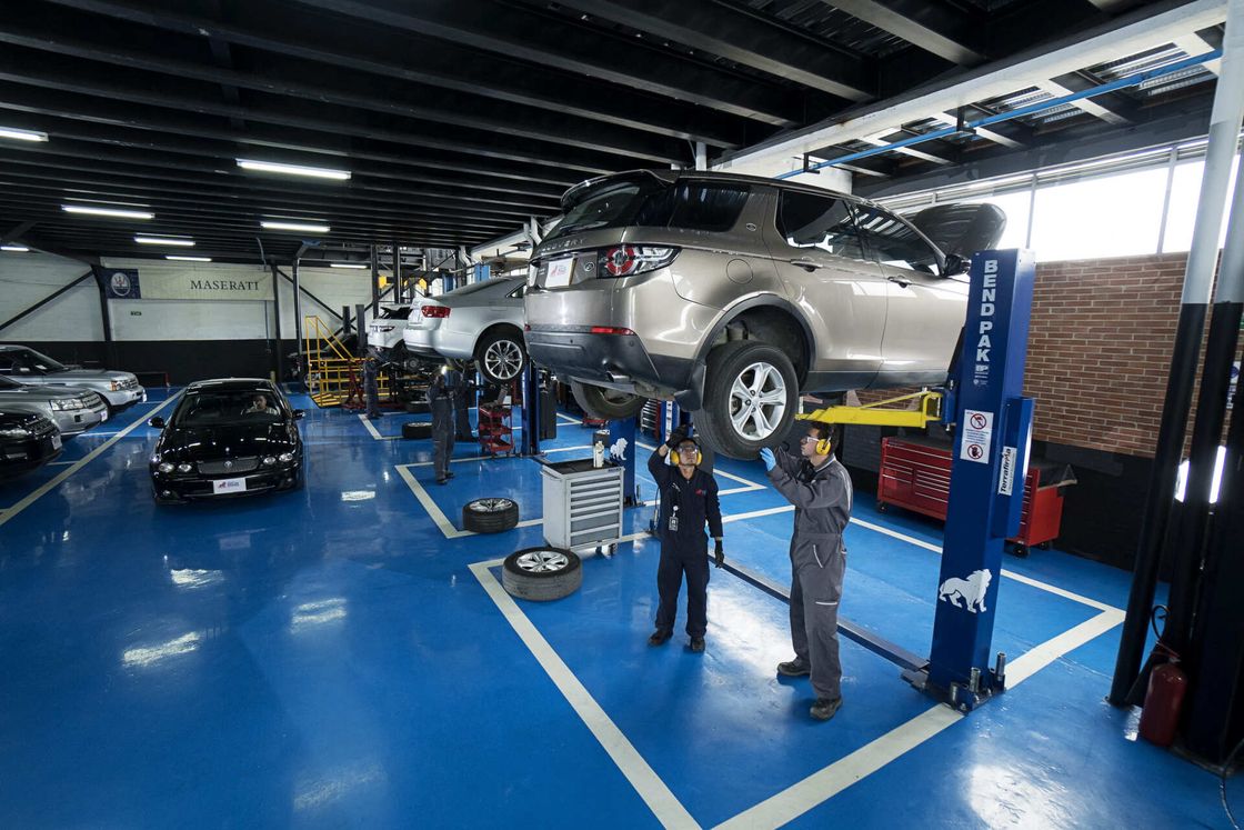 Dos mecánicos están trabajando en un coche en un garaje.