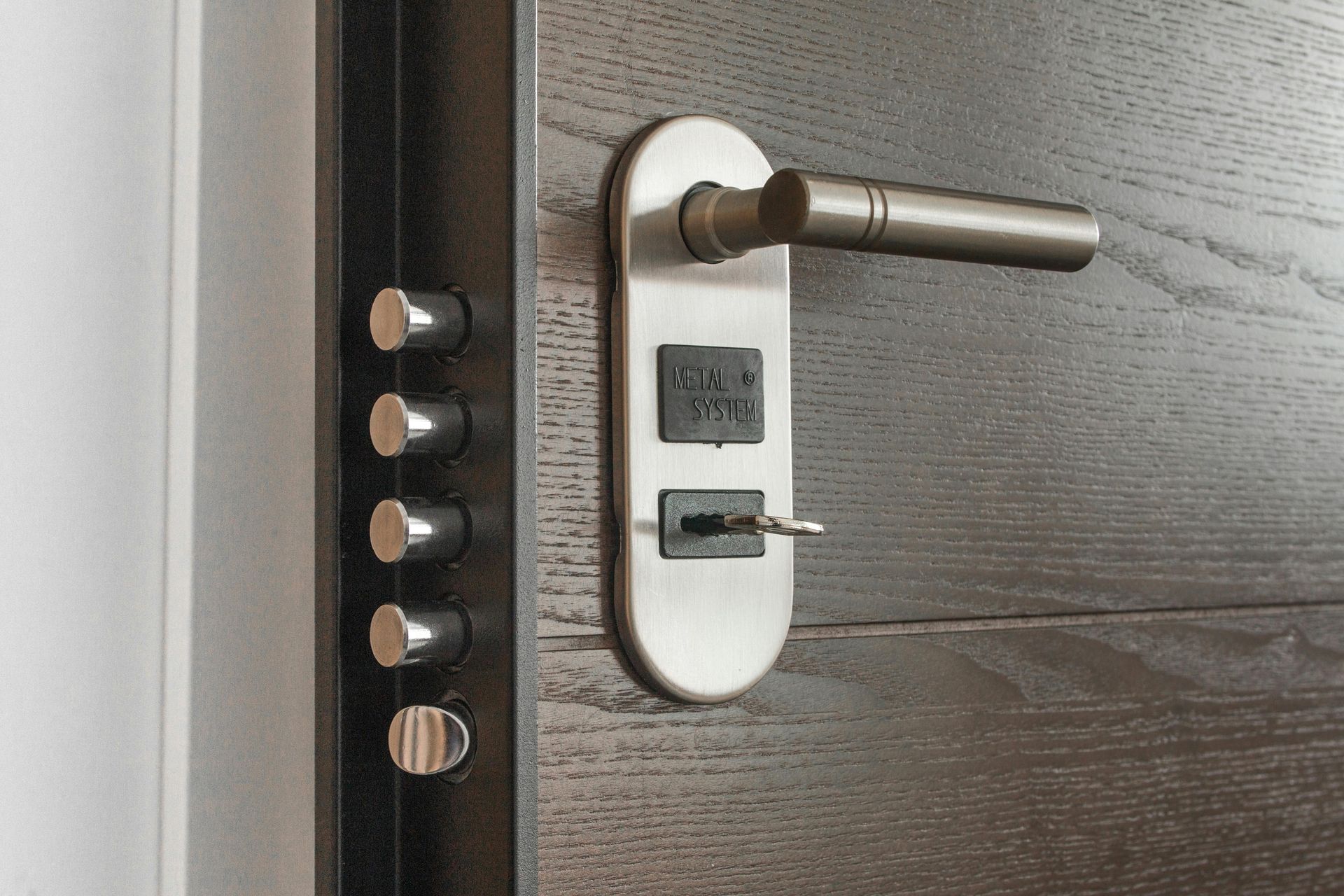 Close-up of a dark wooden door with a silver handle, key, and multiple locking bolts.