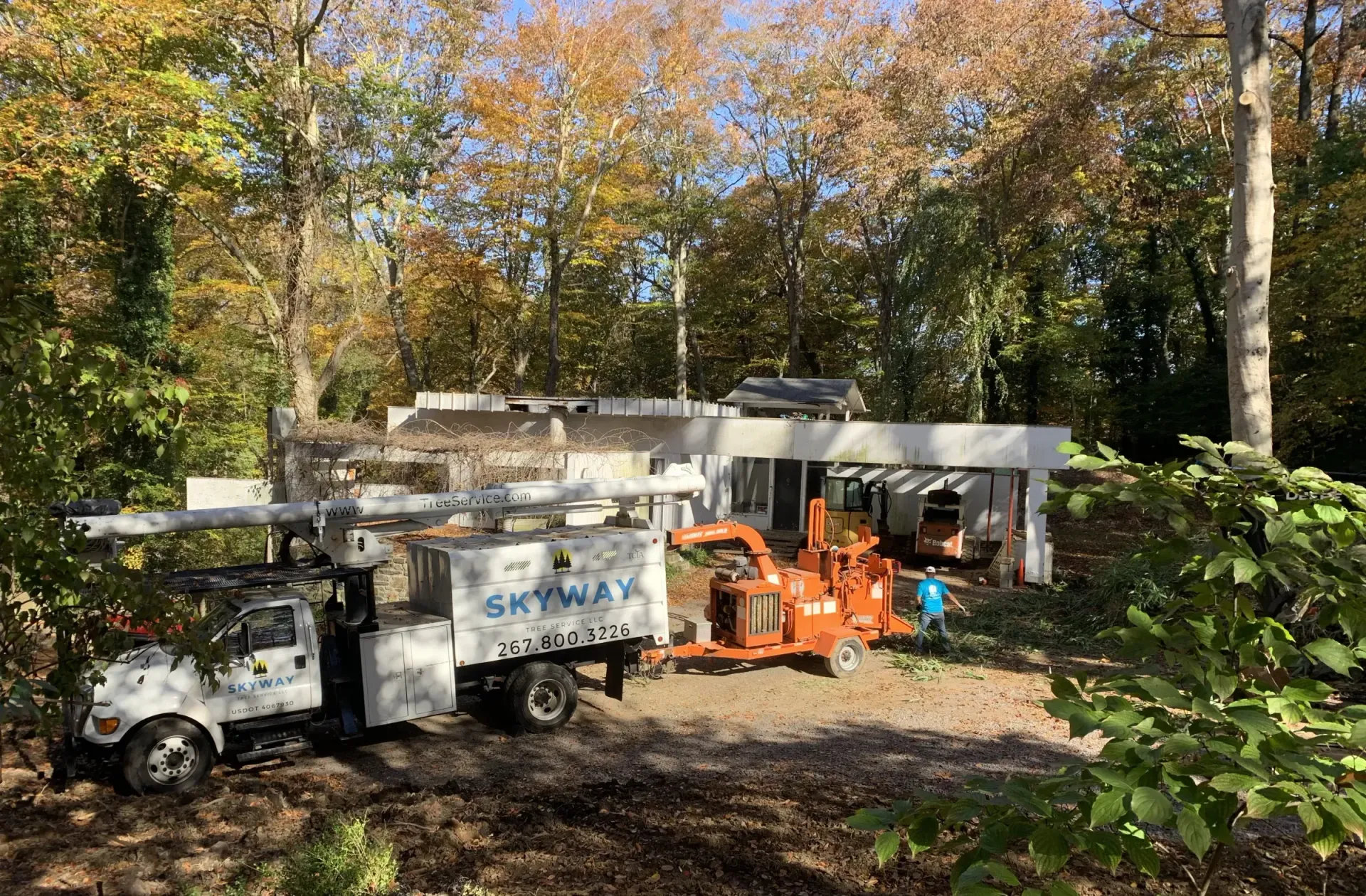 A white truck is parked in front of a house in the woods.