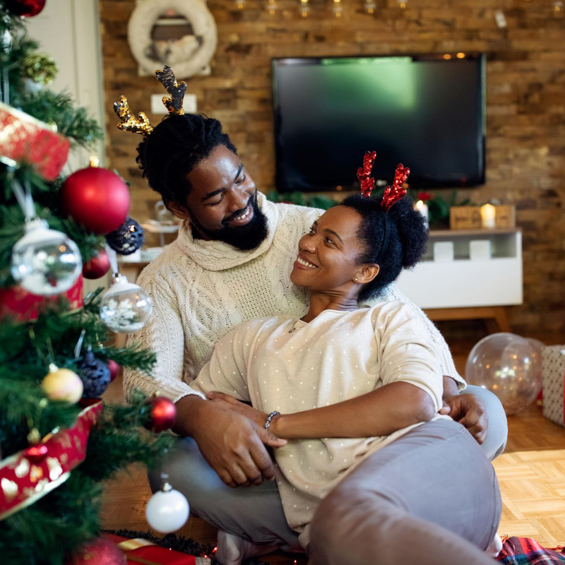 Group therapy: Two women embrace, surrounded by others clapping and smiling in a room with chairs and plants.