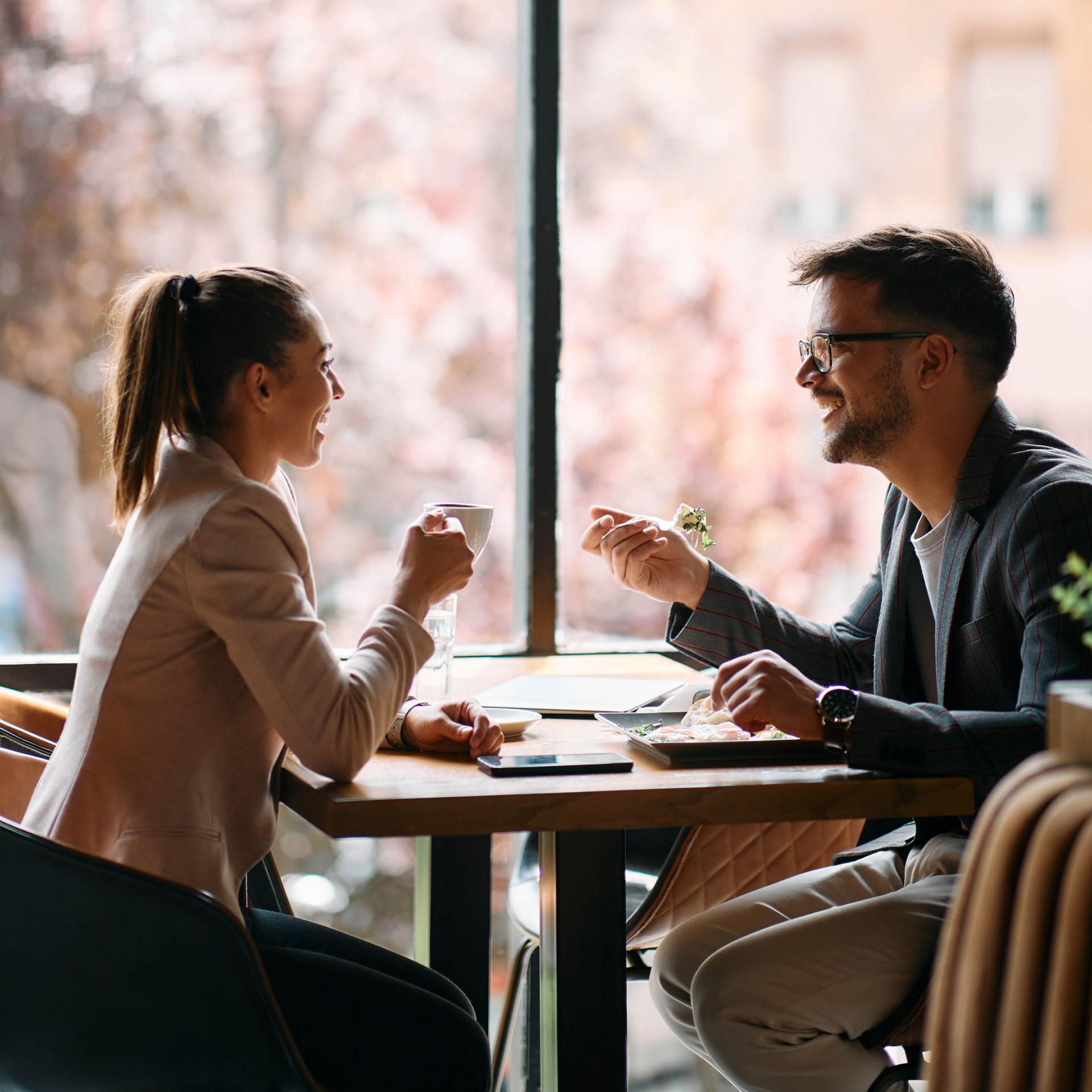 Man in green shirt sits on a couch, hands clasped. A person writes on a notepad.
