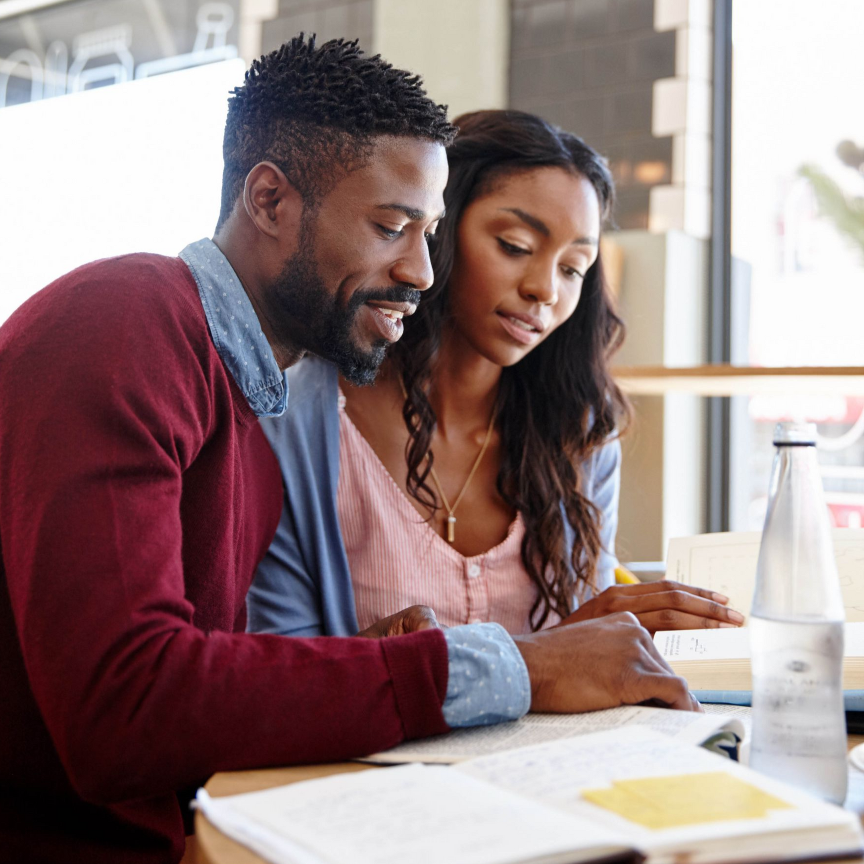 A couple in therapy, talking to a therapist taking notes in a room with neutral decor.