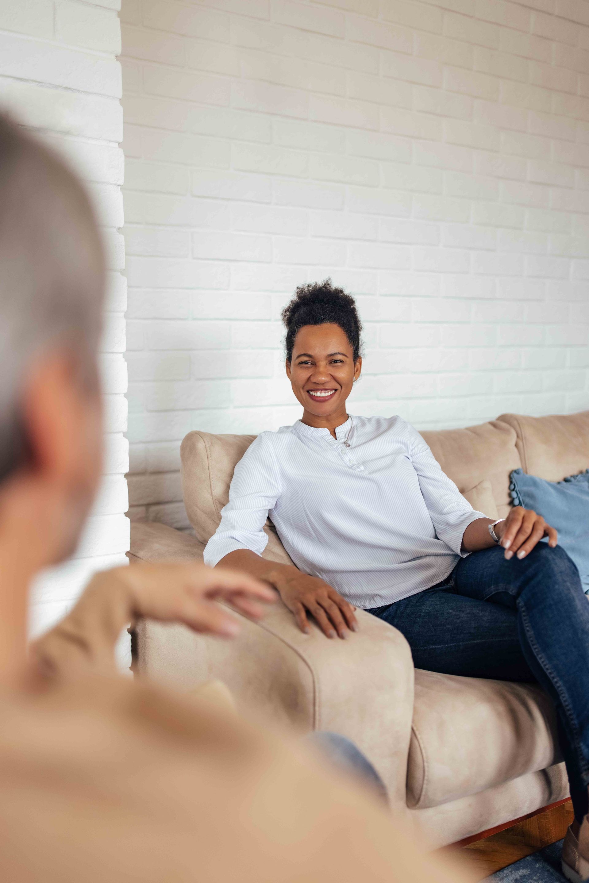 Group therapy: Two women embrace, surrounded by others clapping and smiling in a room with chairs and plants.