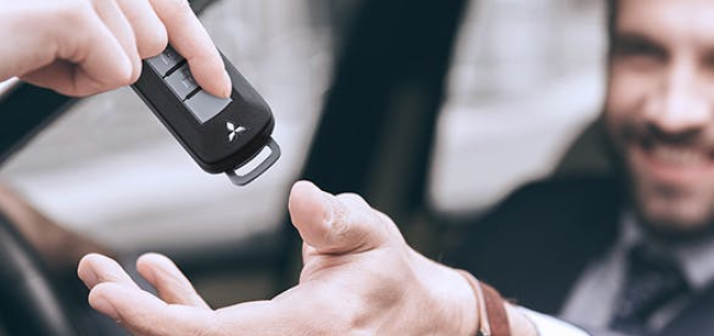 Pessoa entregando as chaves do carro para outra pessoa.