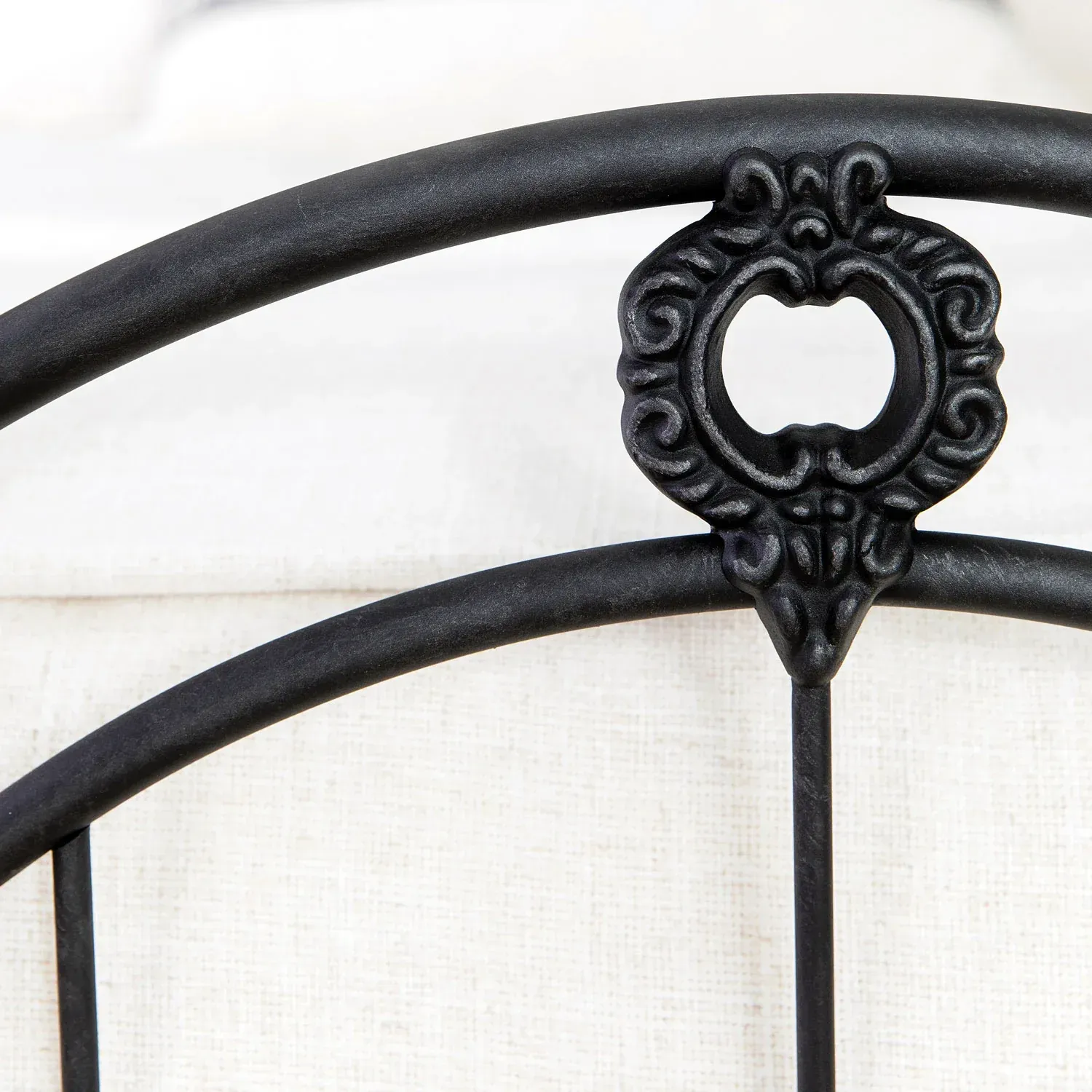 A close up of a black metal bed frame on a bed