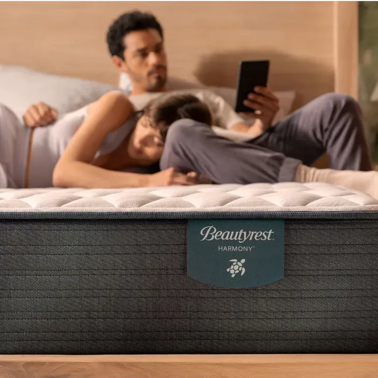 A man and woman are laying on a bed with a beautyrest mattress.
