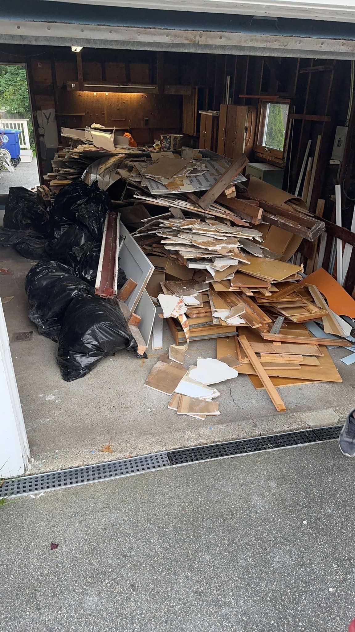 Garage filled with demolition debris and black trash bags.