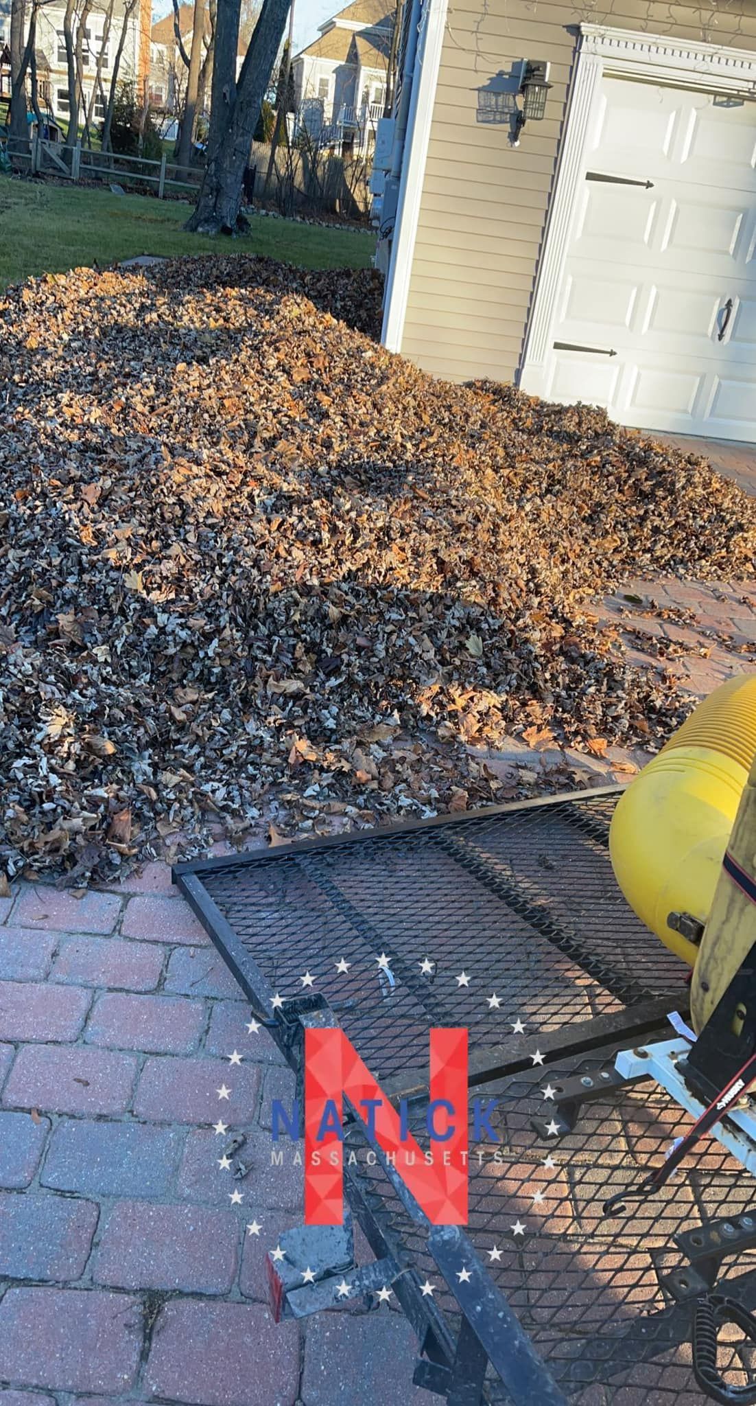 Pile of leaves next to a brick patio and a yellow power tool, marked with a red 