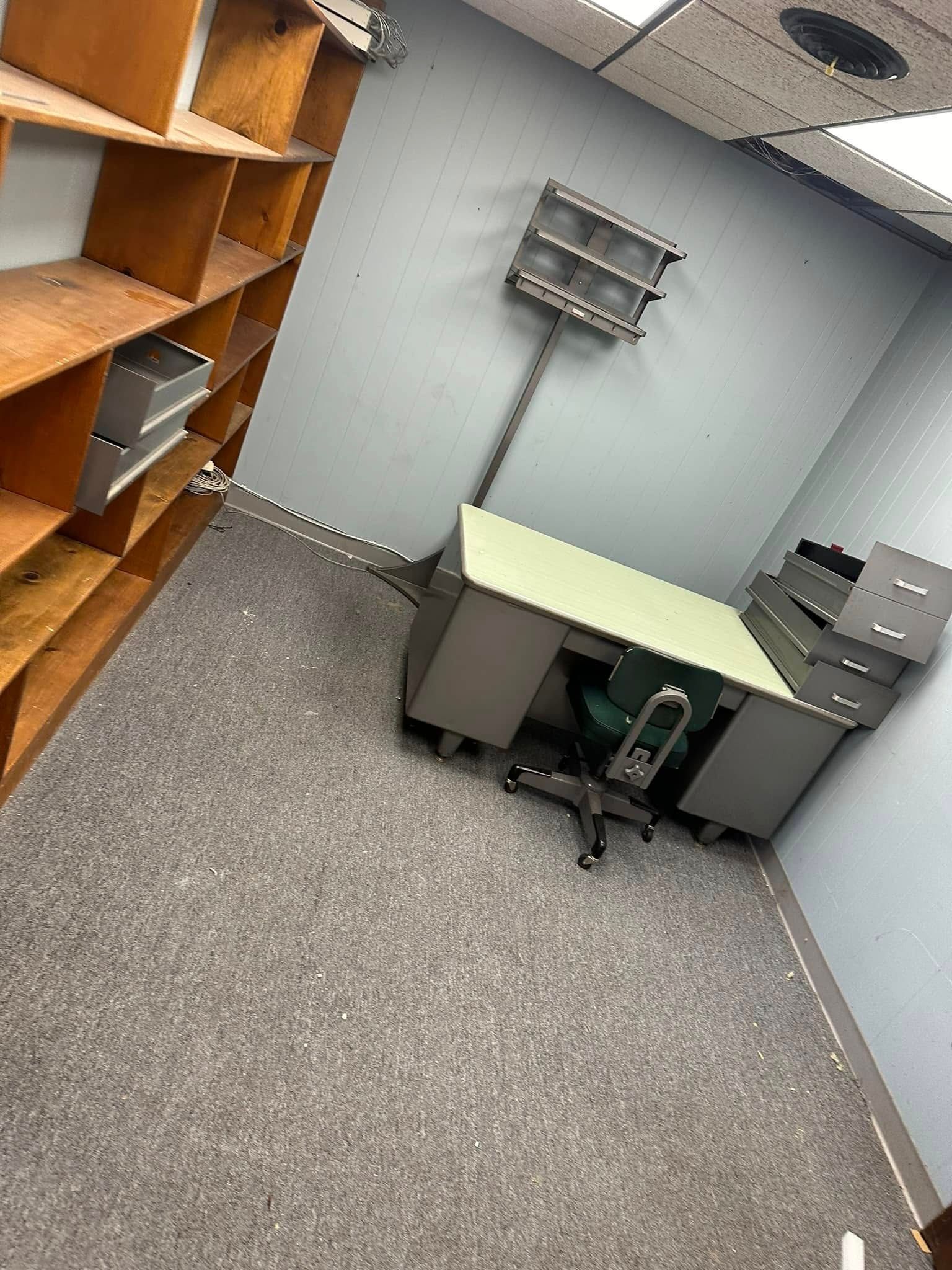 Office space with a desk, shelving, and a gray carpet.