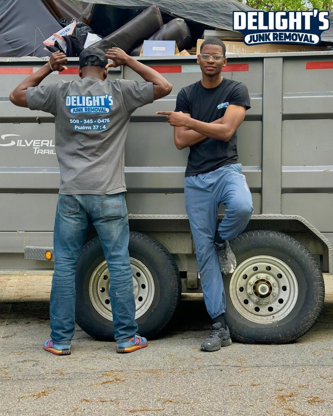 Two men in front of a truck. One points, the other stretches. 
