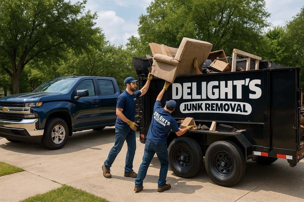 Two men loading junk into a trailer, labeled "Delight's Junk Removal," next to a blue pickup truck.