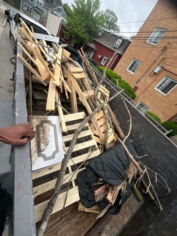 A dumpster overflowing with wood scraps, branches, and debris. Buildings in the background.