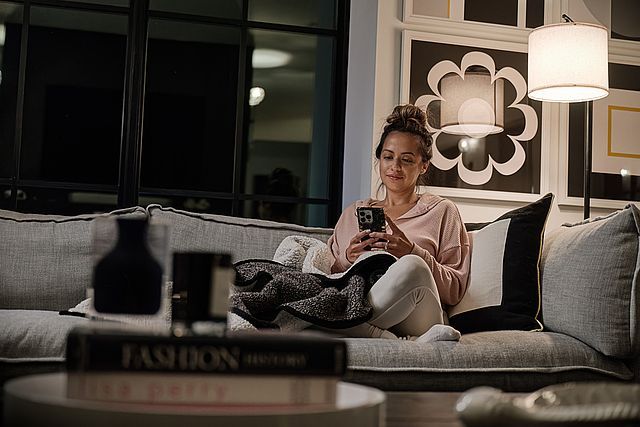 A woman is sitting on a couch looking at her phone.