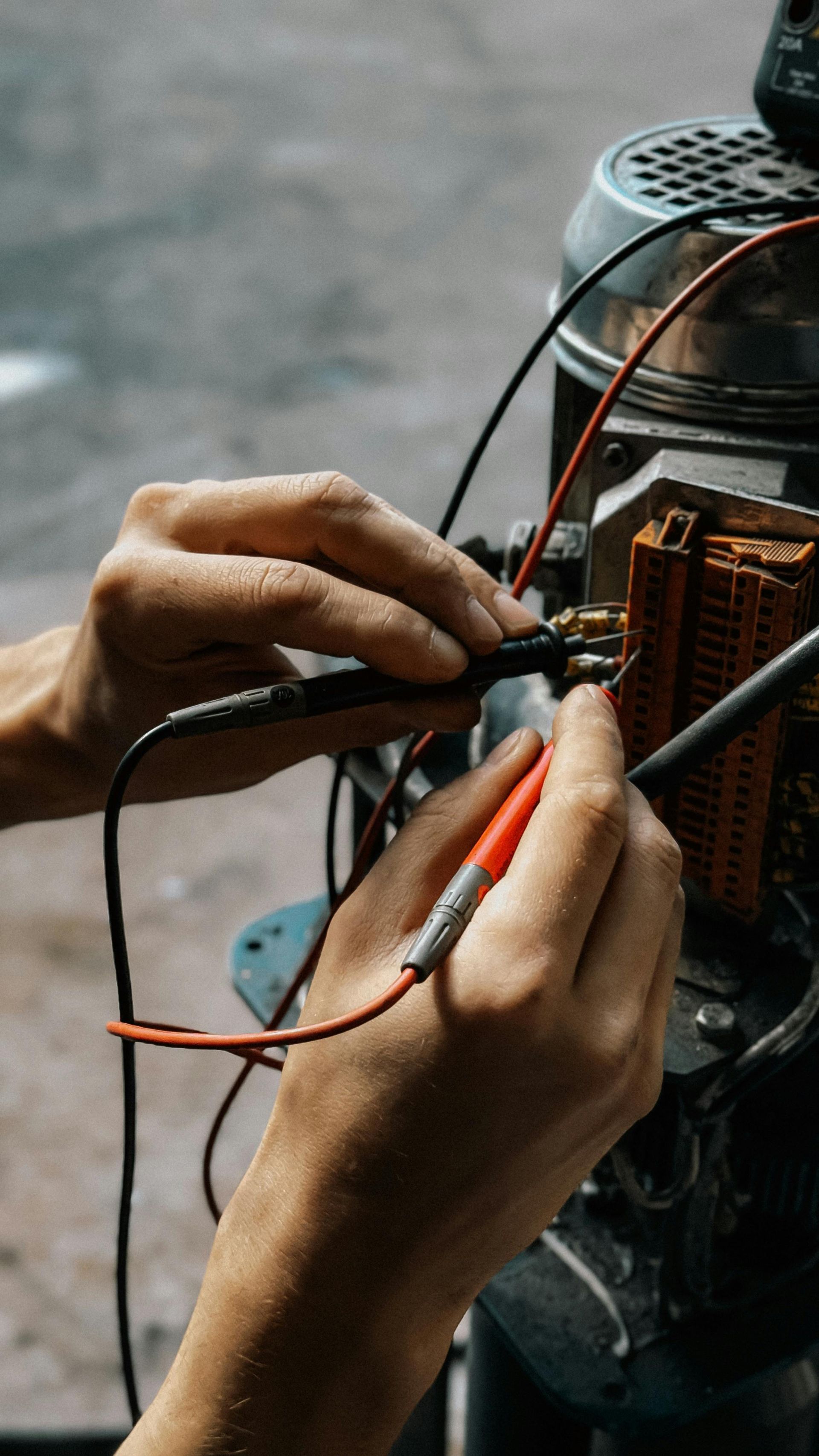 electrician testing electrical components of a machine with wires and meter.