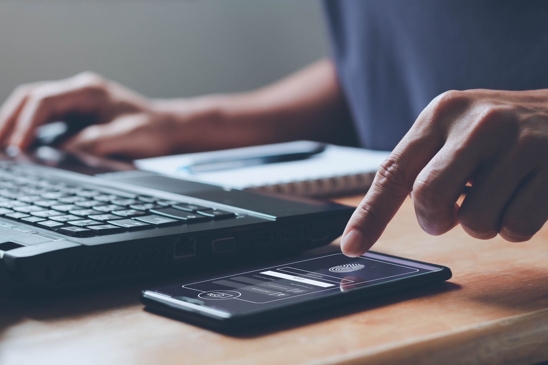 Una persona está usando una computadora portátil y un teléfono celular al mismo tiempo.