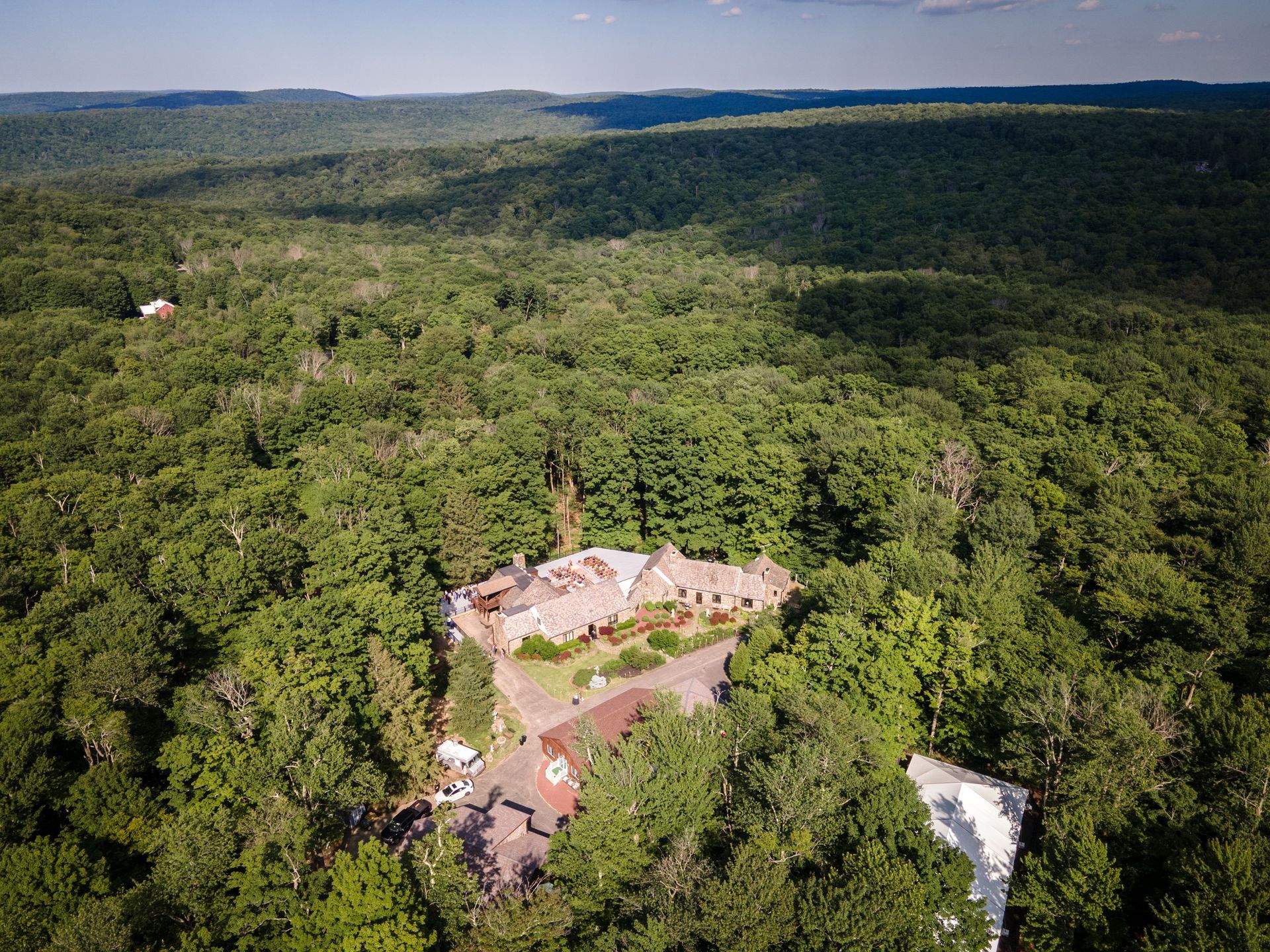 An aerial view of a house in the middle of a forest.